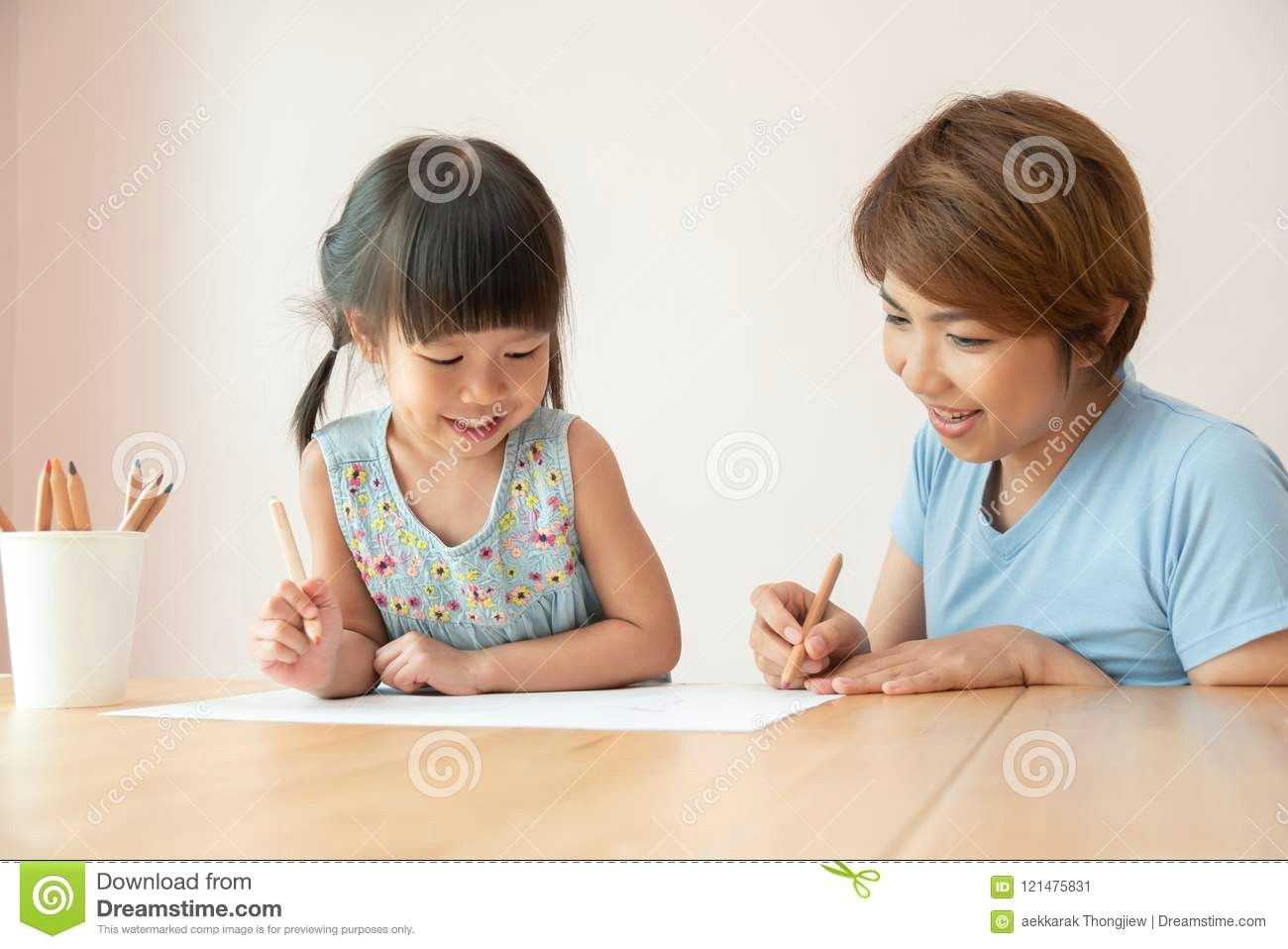 happy asian mother and daughter drawing together