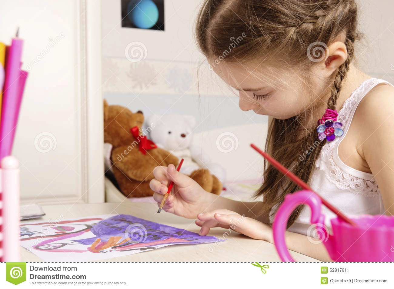 portrait of young girl of 6 or 7 years old she is pretty pig tailed brunette girl is sitting behind table and drawing picture with paints