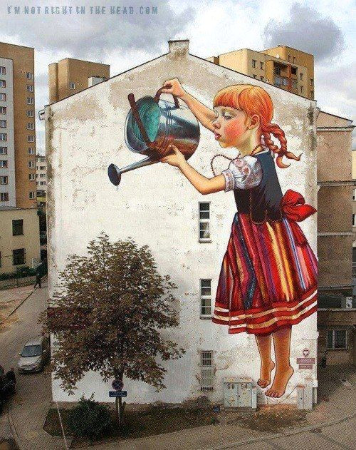 is that a drawing inside a drawing about a person who drew a little girl on the side of a building watering a tree or is it a real photographic picture