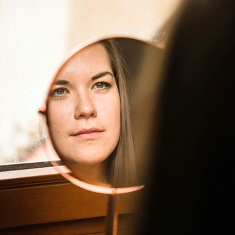 woman looking at her face in mirror