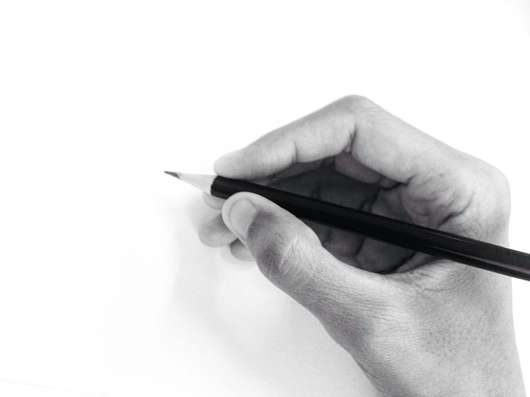 cropped hand of person holding pencil by white wall