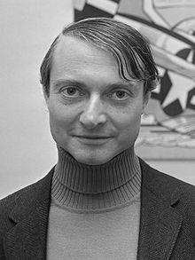 a black and white portrait photograph of a man at bust length facing and