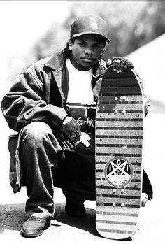 eazy e poses with a natas kaupas devil worship model skateboard and a